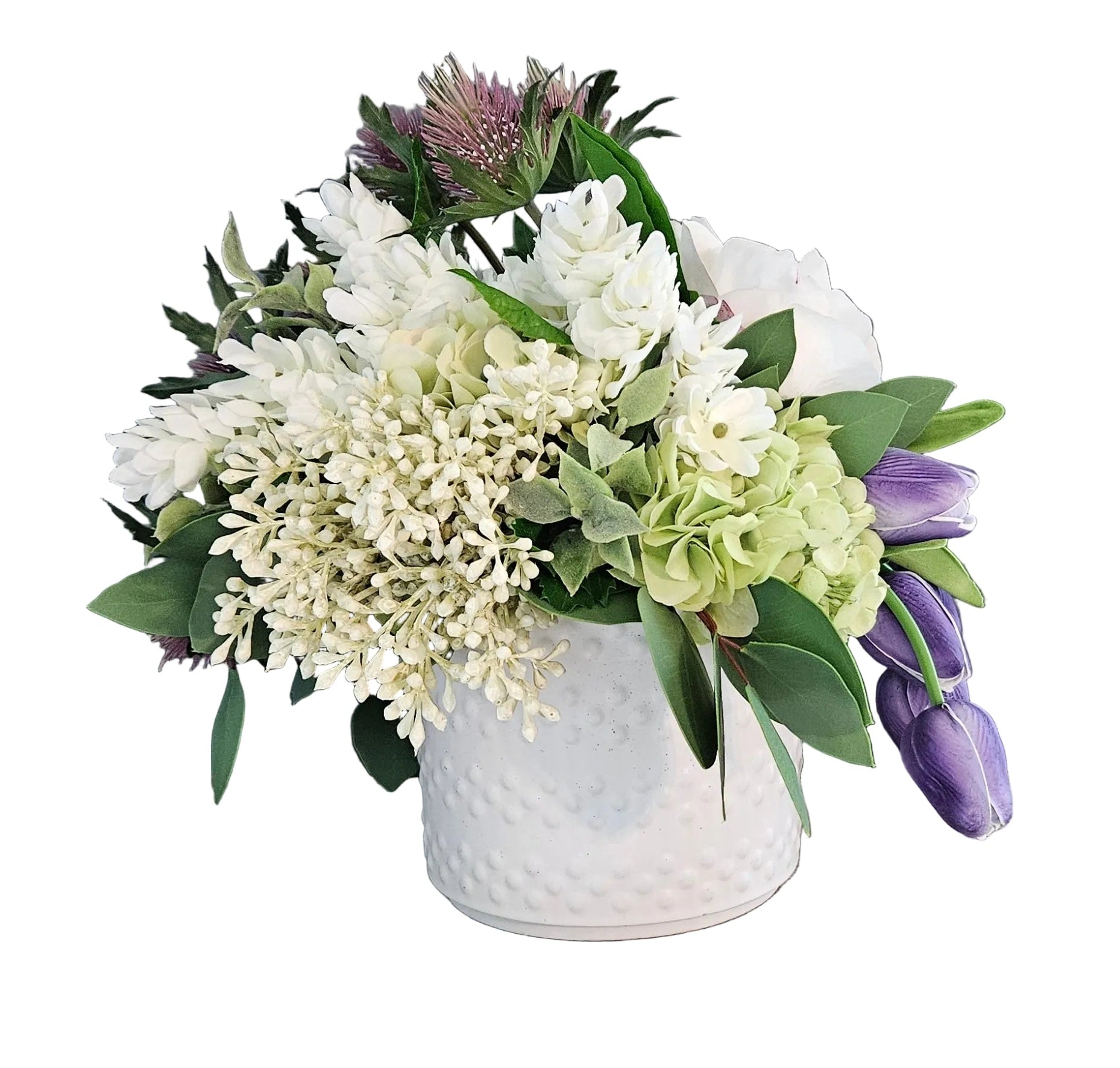 Floral arrangement in a white vase on a wooden surface with a gray wall background